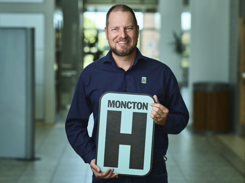 Dr. Ken Gillespie Holding H Sign and Smiling at camera