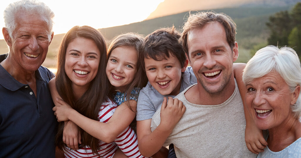 Multi generational family in a field smiling