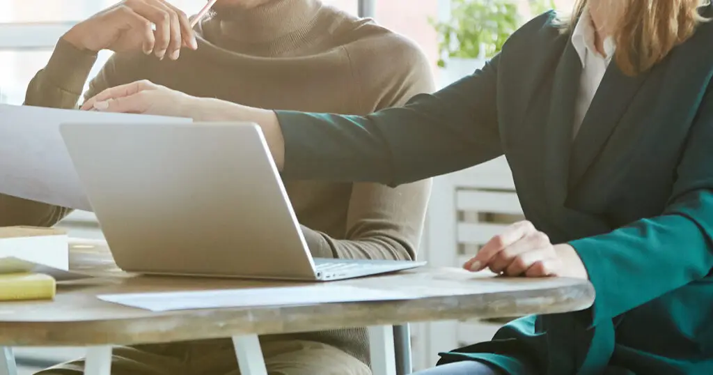 Two people at a desk looking at a laptop screen